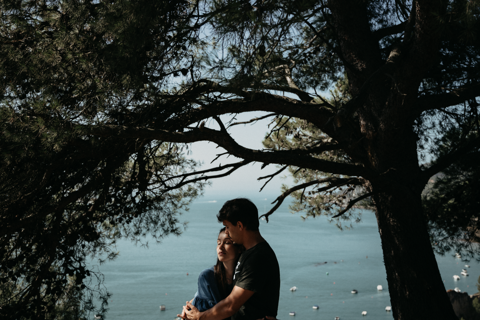 Couple hugging under a tree beside the water