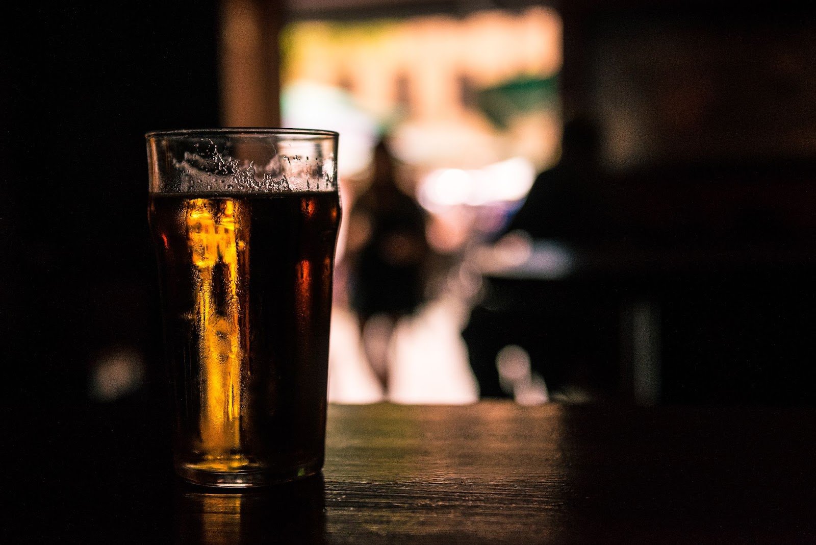 Glass of beer on a bar counter in warm low light