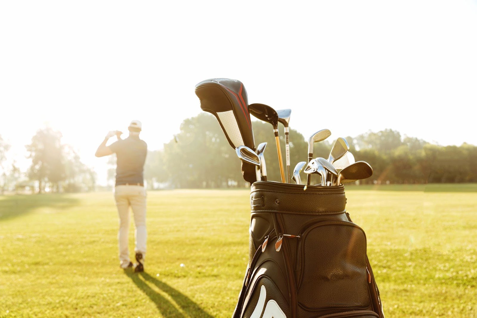 Golfer walking on a sunny golf course with a bag of golf clubs